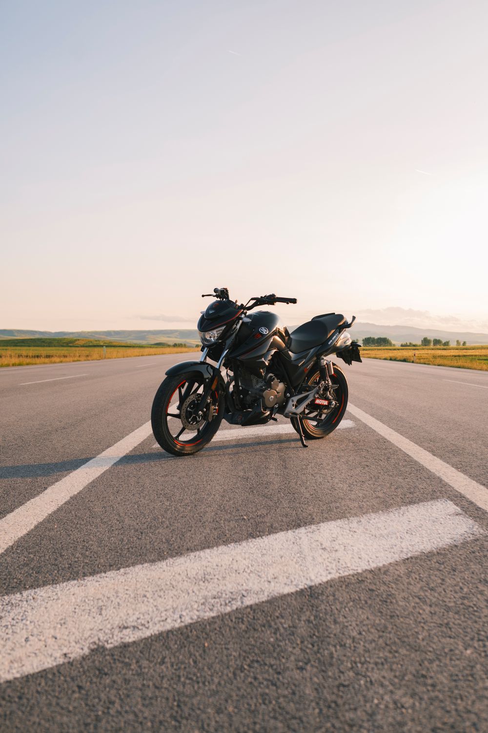 Moto aparcada en una carretera junto a un paisaje abierto